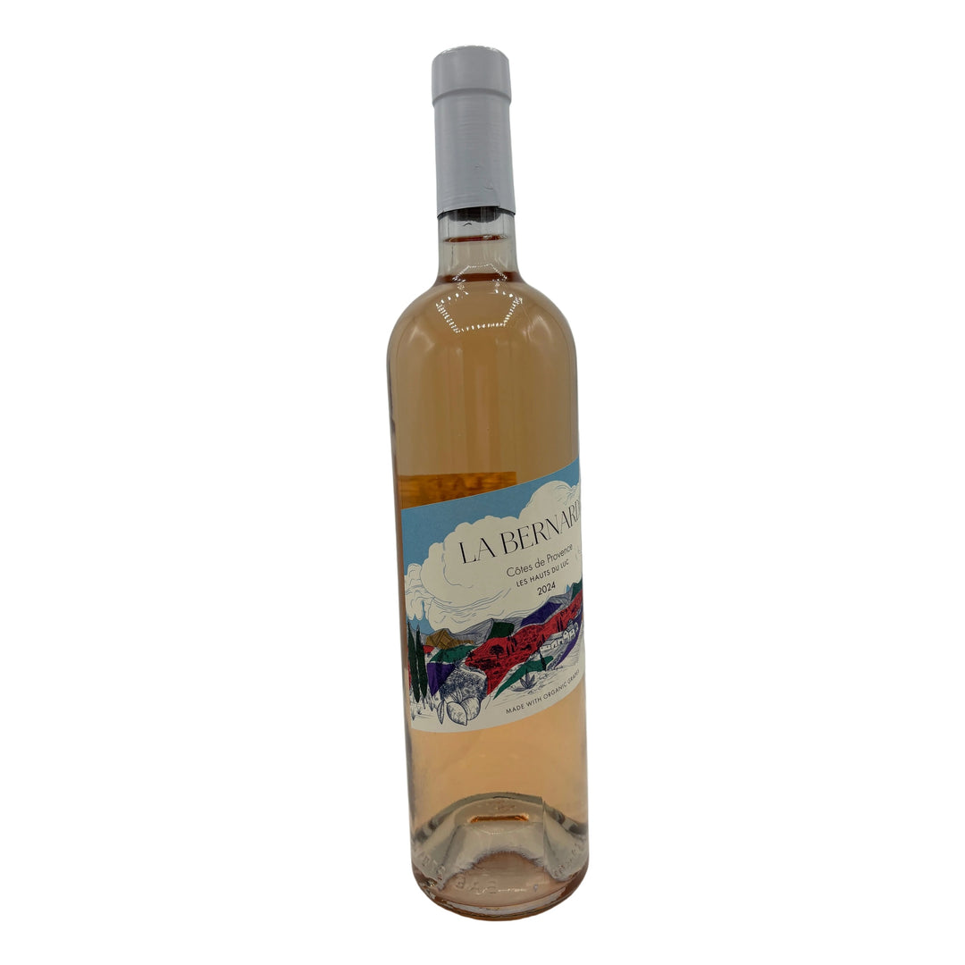 Picture of a wine bottle containing rose. The label showcases a colorful drawing of a mountainous village. 